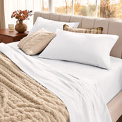 Neatly made bed with organic flannel sheets  and a beige blanket in a bright bedroom.