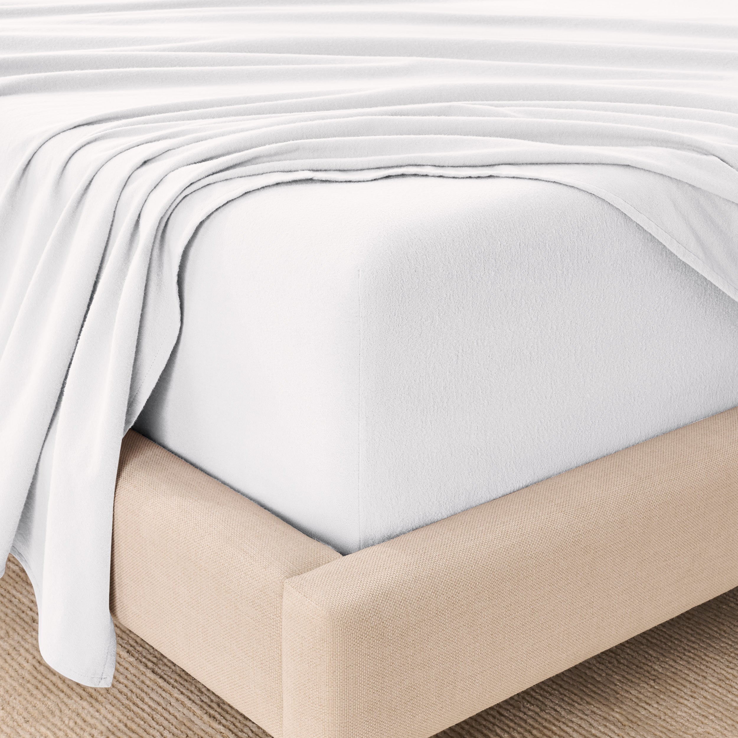 Fitted sheet and top sheet on a mattress with a beige bed frame