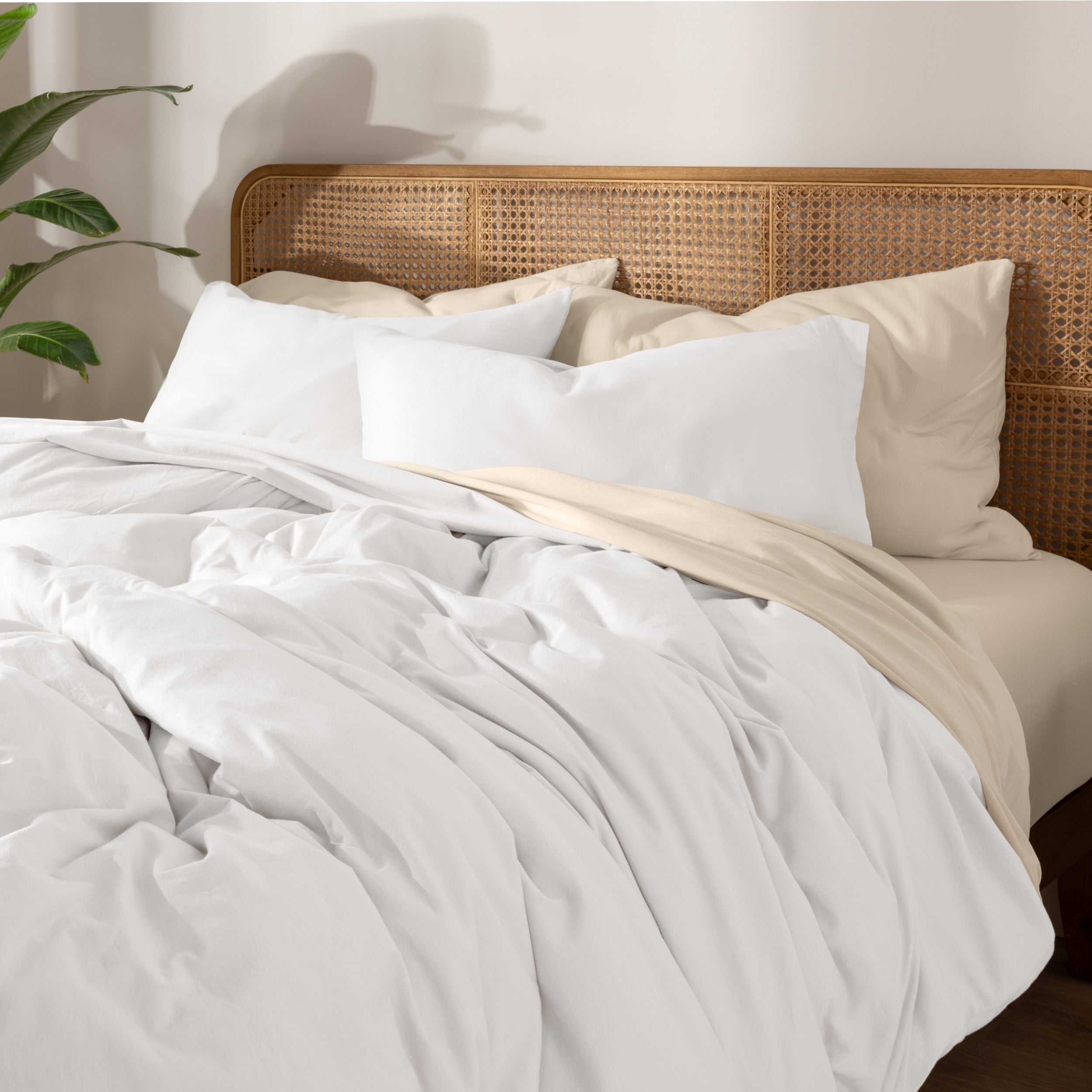 A neatly made bed with white bedding, white pillows, and a wooden headboard. 