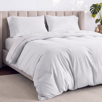 A neatly made bed with white bedding, white pillows, and a wooden headboard. 