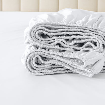 Folded fitted sheet on a bed with a neutral background