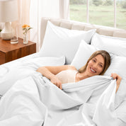 Woman lying in bed with percale bedding in a bright bedroom