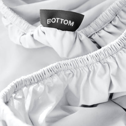 Close-up of a fitted sheet with a black fabric brand label reading BOTTOM.