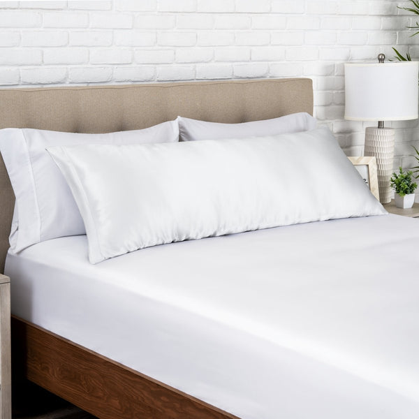 White satin pillow on a bed with white bedding and a wooden headboard.