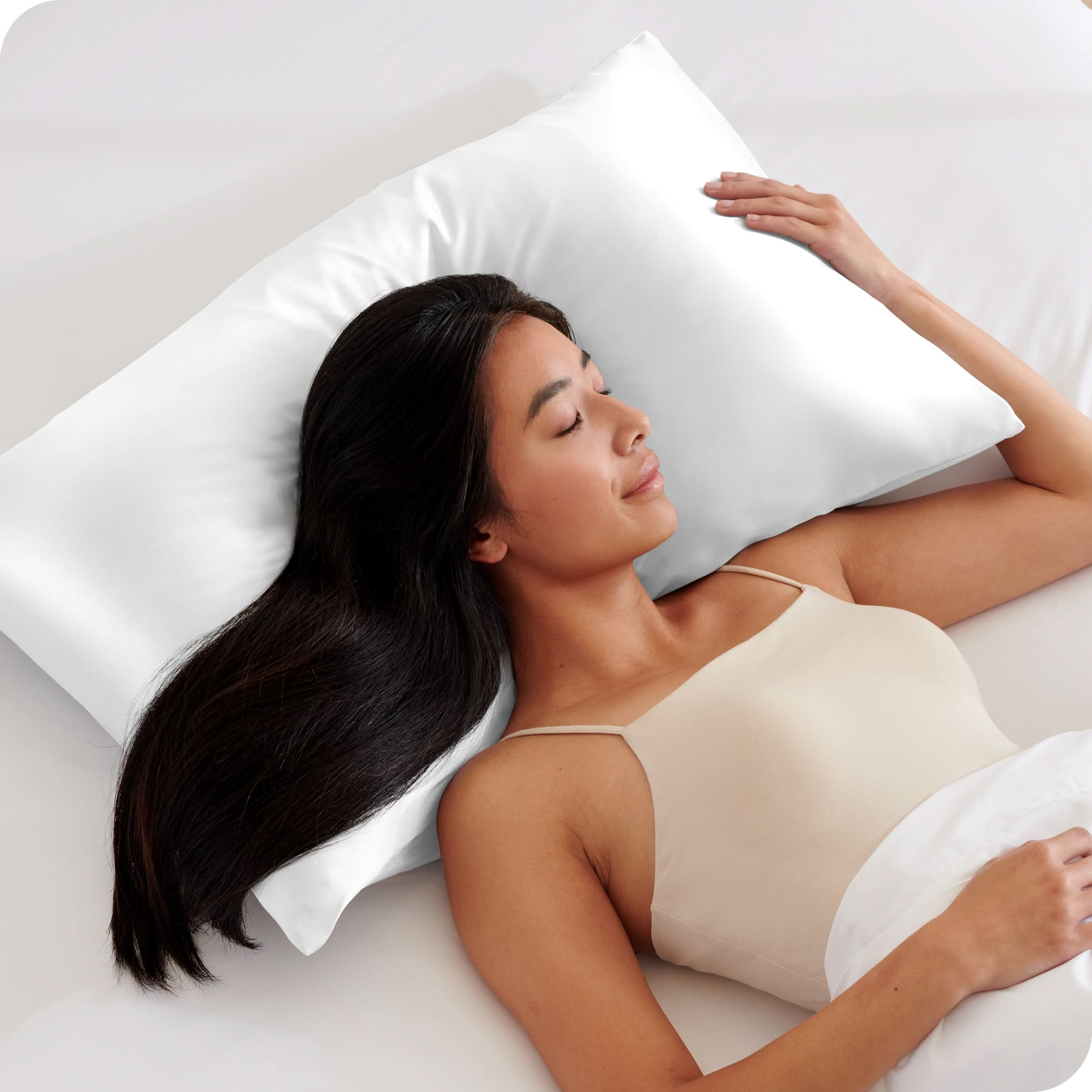 A woman is sleeping on a pillow with a satin pillowcase