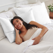 Woman lying on a bed with satin pillows and white bedding