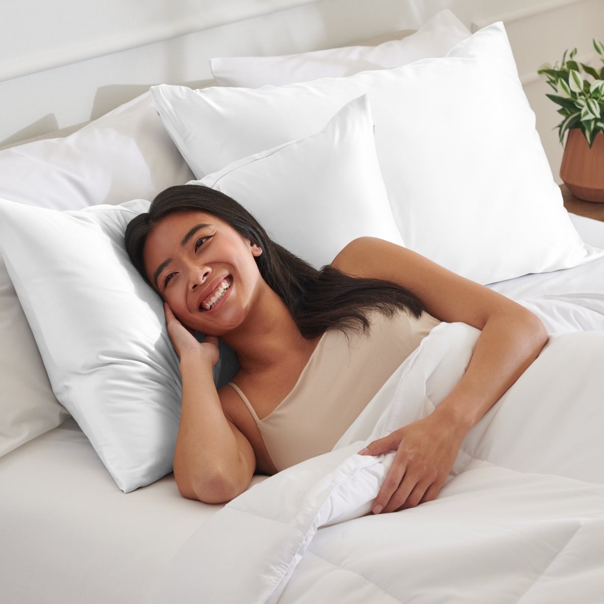 Woman lying on a bed with satin pillows and white bedding