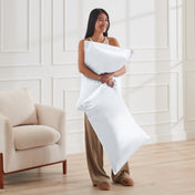 Woman holding 2 pillows with satin pillowcases on them