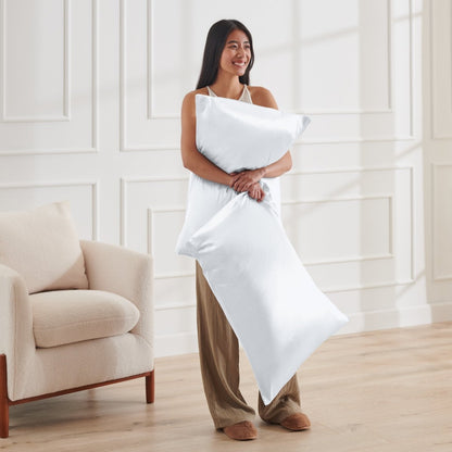 Woman holding 2 pillows with satin pillowcases on them