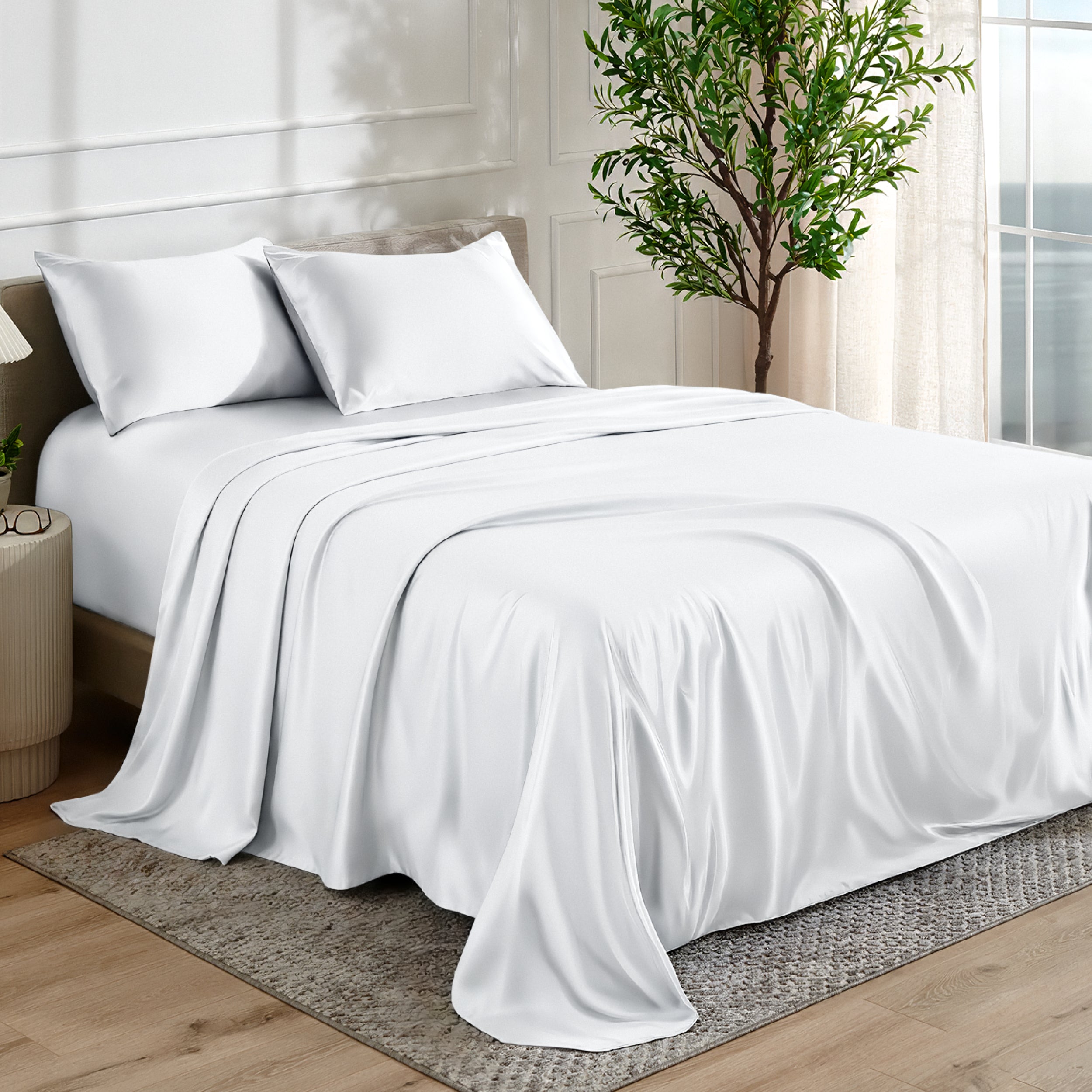 Satin sheet set on a bed in a bedroom with a plant and window in the background.