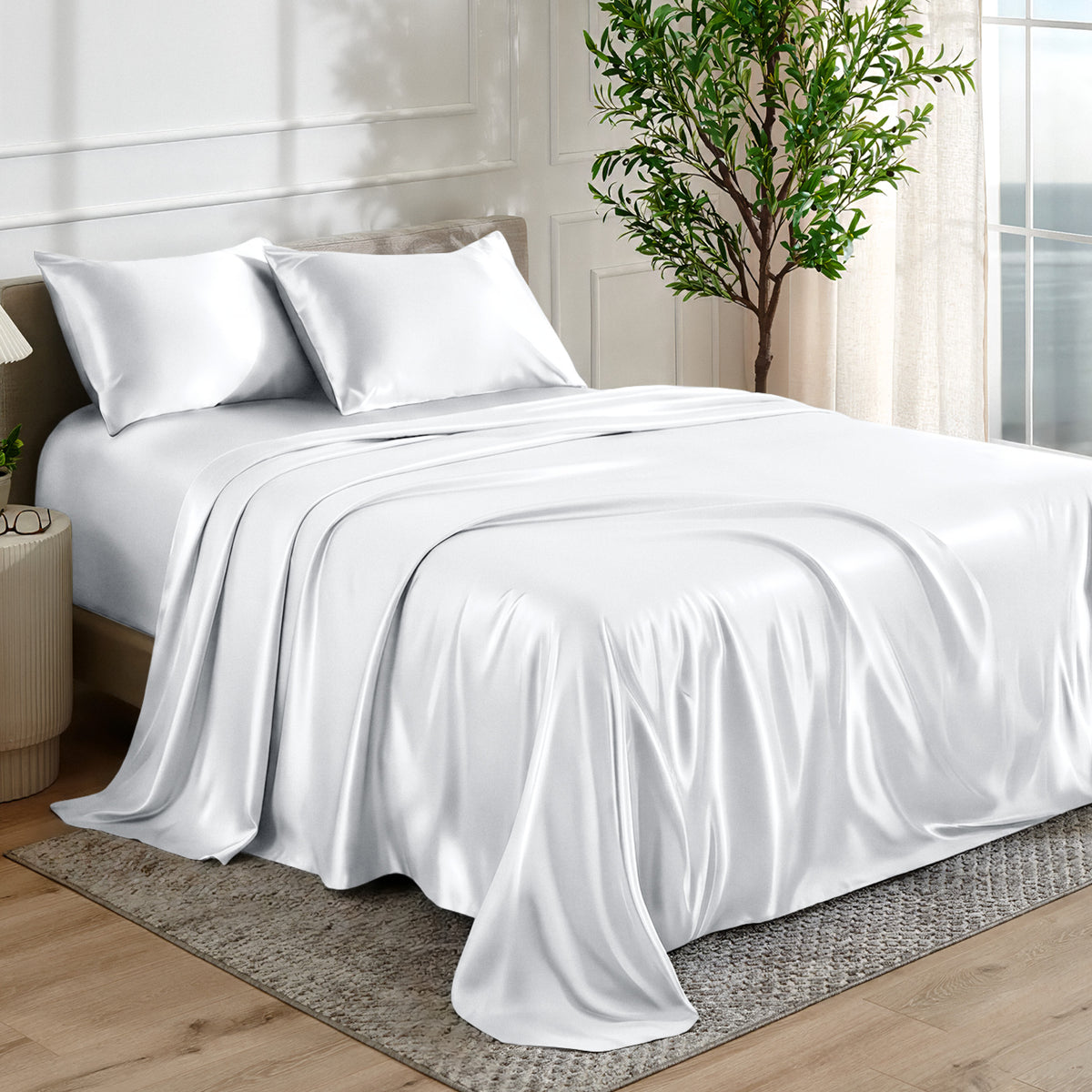Satin sheet set on a bed in a bedroom with a plant and window in the background.