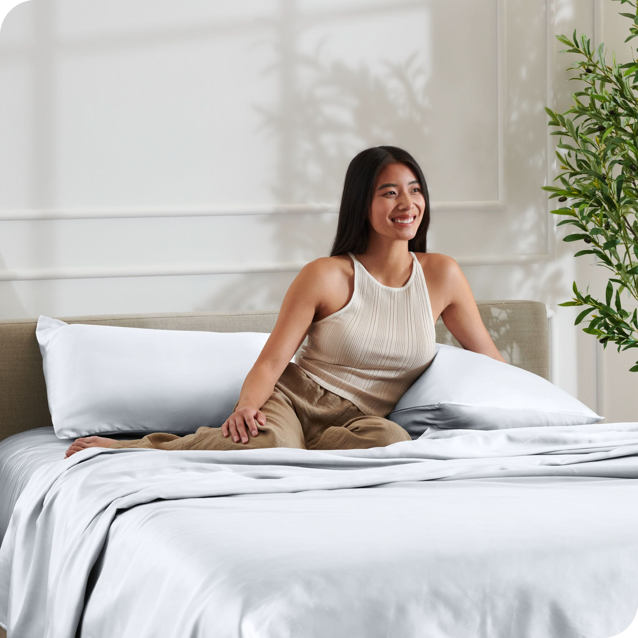 A woman is resting on a bed make with satin sheets