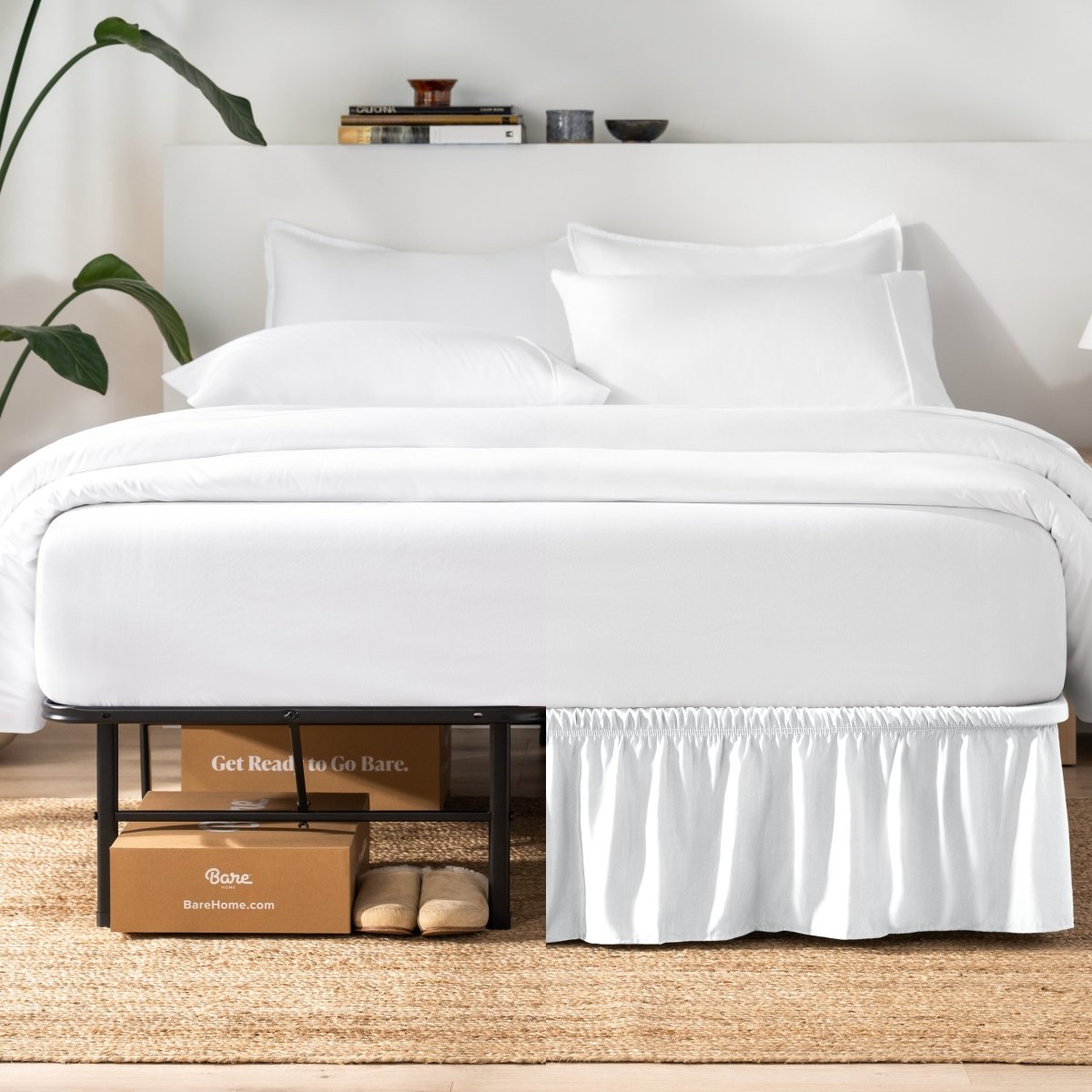 Bed with white bedding and a plant near the bed.