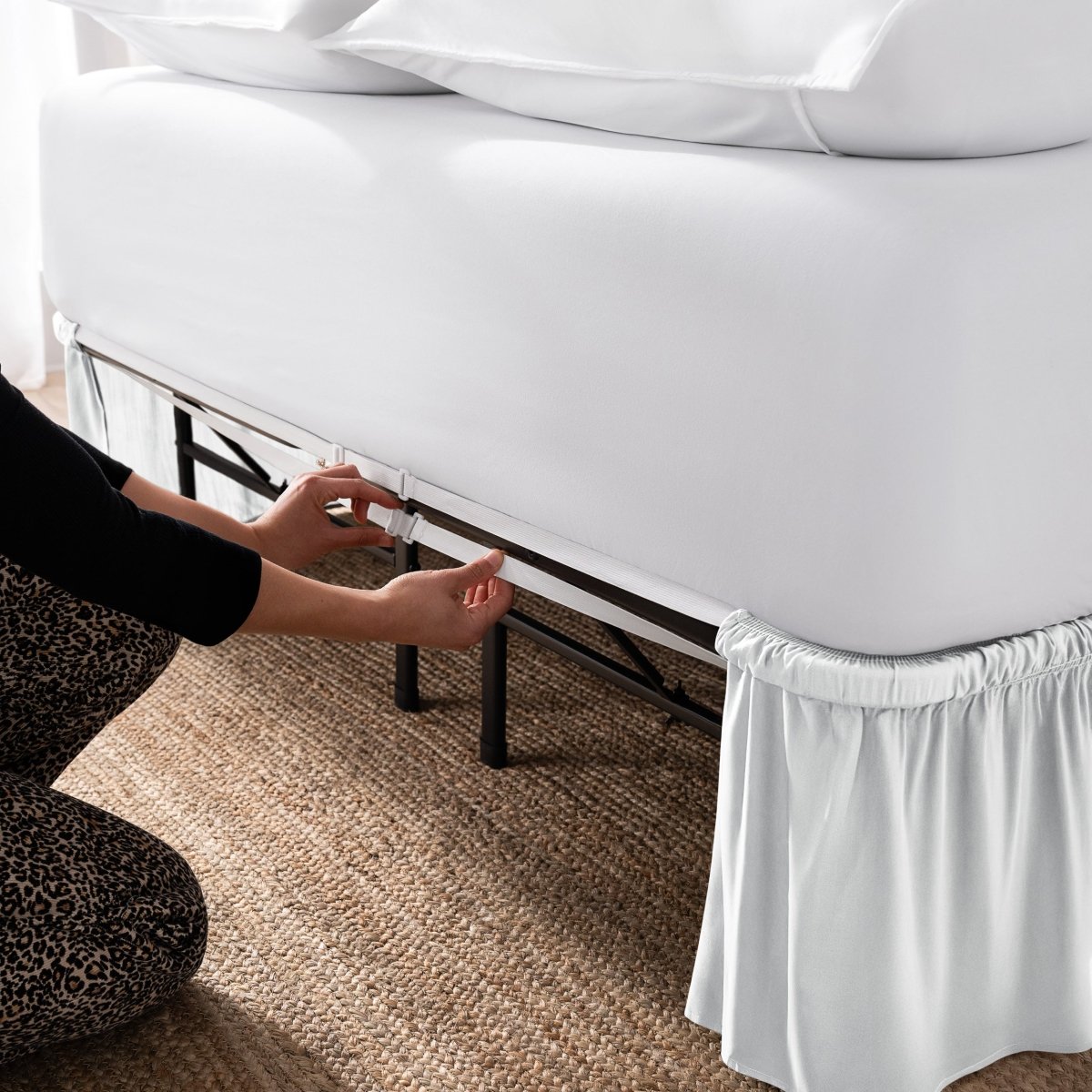 Adjustable bed skirt on a bed showing the elastic strap.