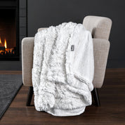 Sherpa blanket draped over an armchair in front of a fireplace.