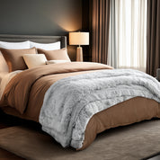 Neatly made bed and a textured throw blanket  over the end of the bed.