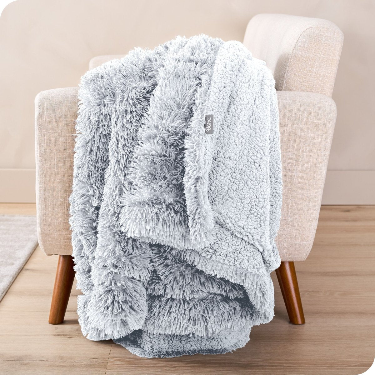 A shaggy faux fur blanket draped over the arm of a chair