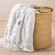 A blanket hanging over the edge of a wicker basket