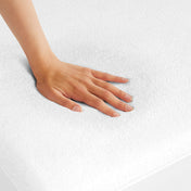 A woman is pressing her hand down a mattress with a terry cotton mattress protector on it