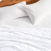 Close up of a weighted blanket on a bed next to pillows