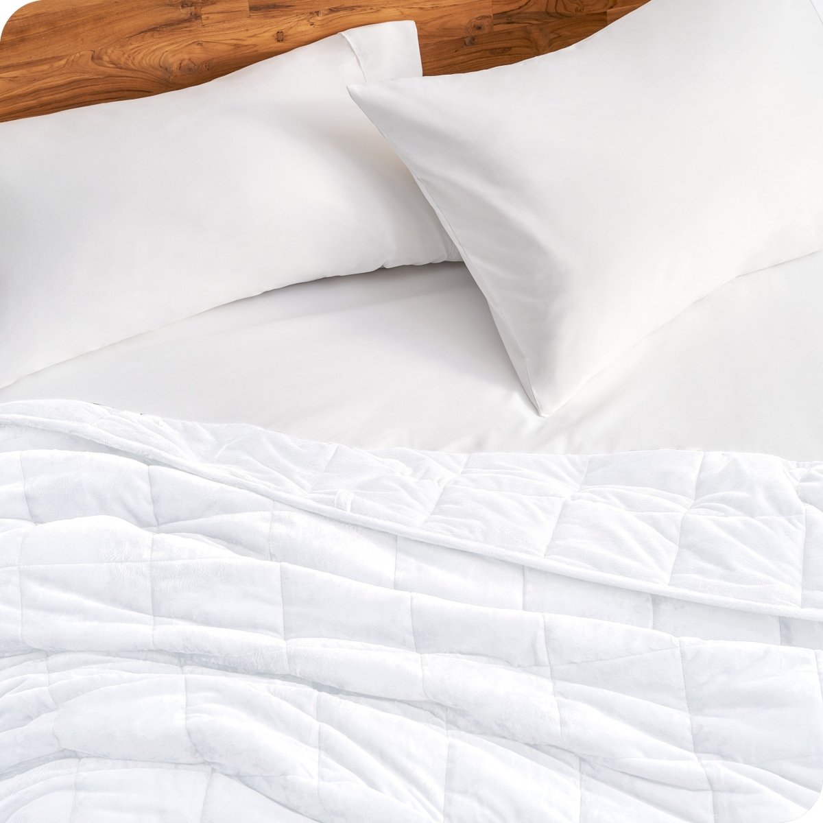 Close up of a weighted blanket on a bed next to pillows