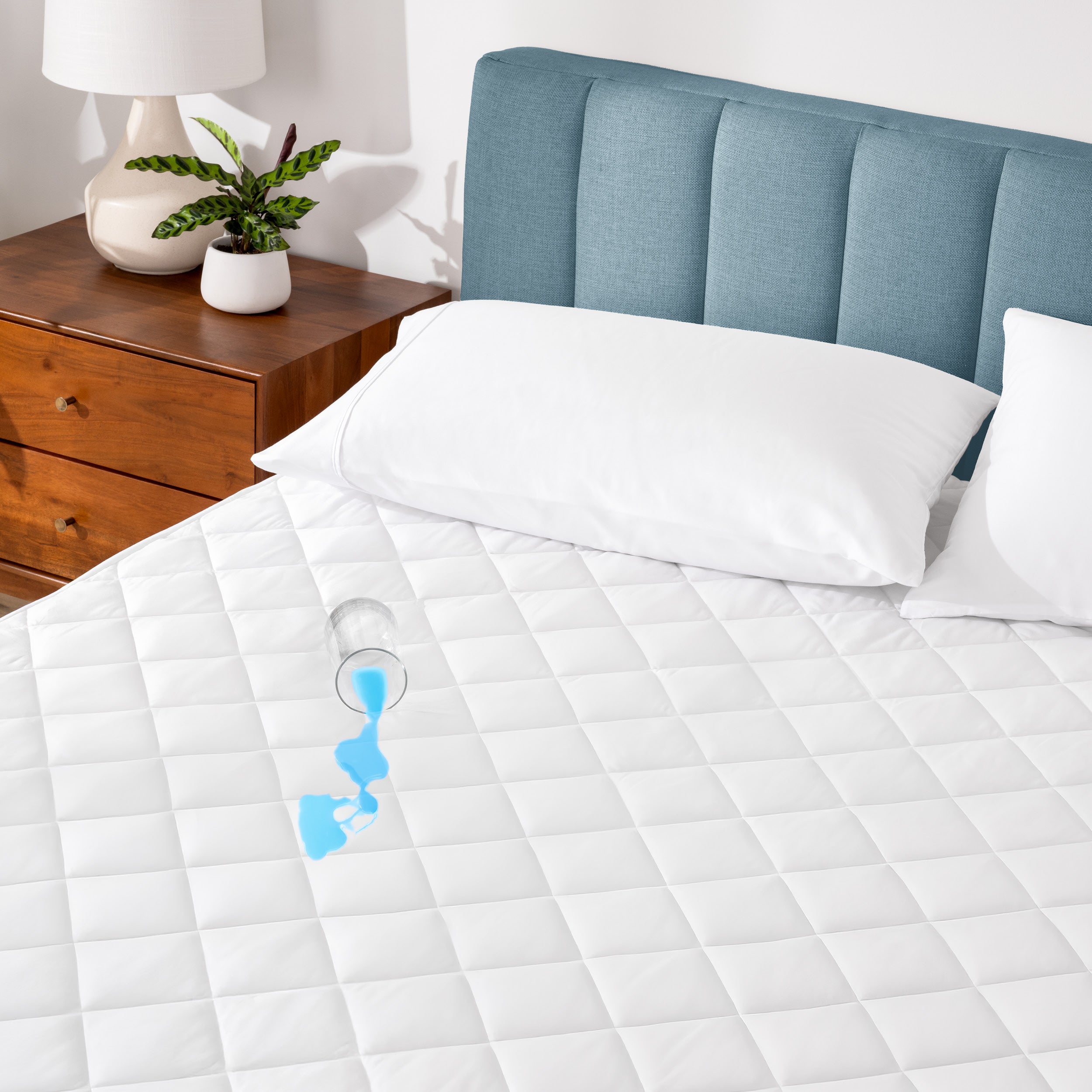 A glass of water spilled on a waterproof mattress pad