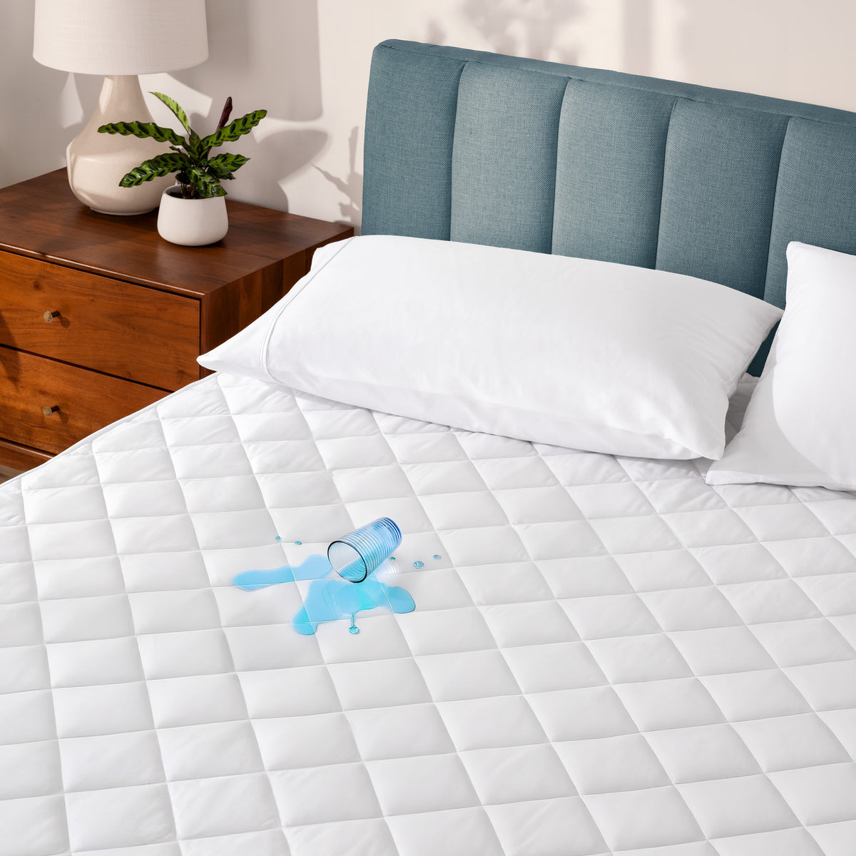 A glass of water spilled on a waterproof mattress pad