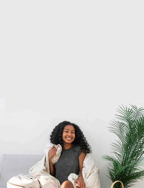 Women sitting on grey couch wrapped in a Duvet