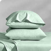 Pillows inside percale pillowcases stacked on a bed
