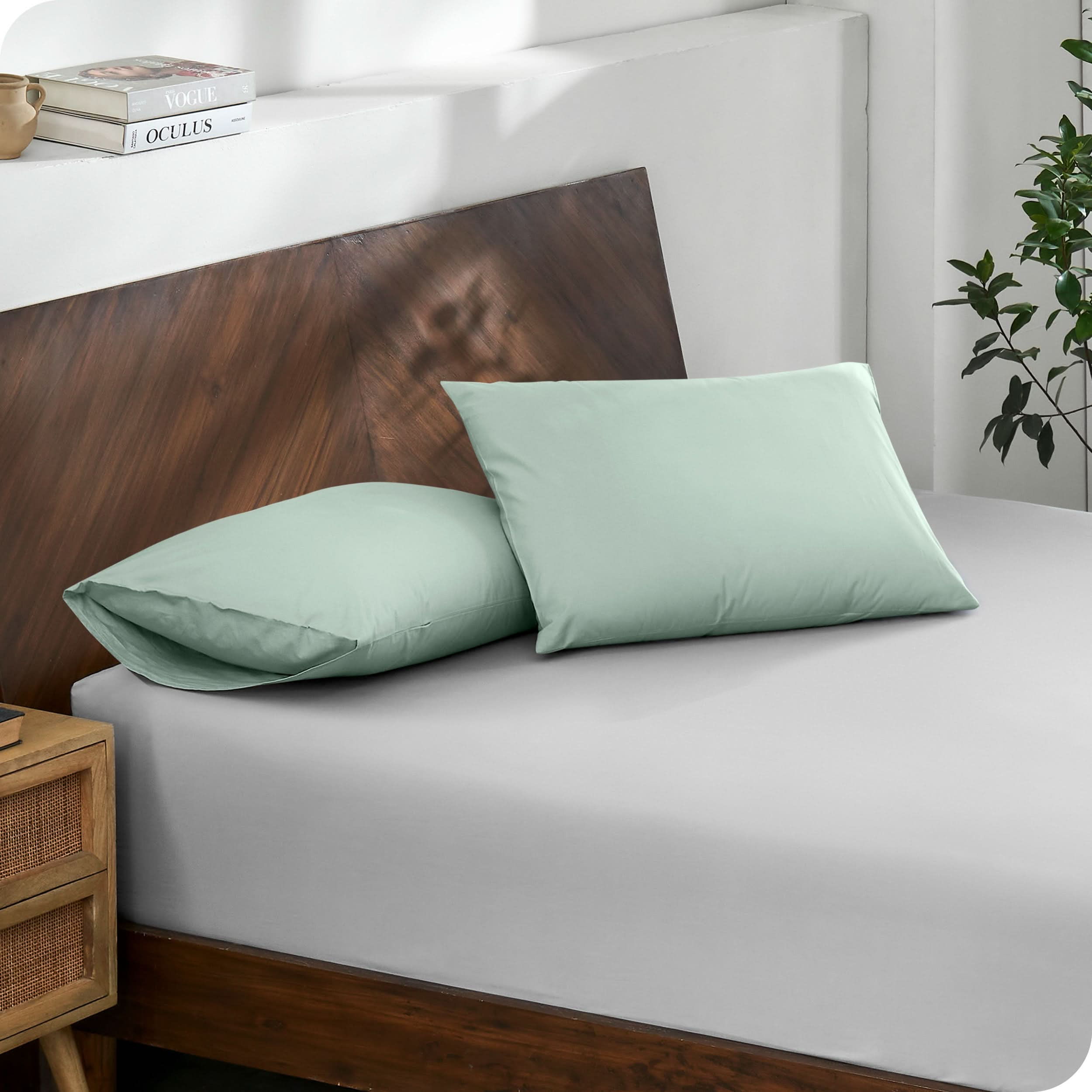 Diagonal view of modern wood bed with a fitted sheet and pillowcases