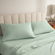 Percale bed sheets and pillowcases on a neatly made bed with a beige headboard.