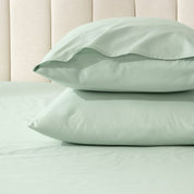 Two pillows stacked on a bed with percale pillowcases on them