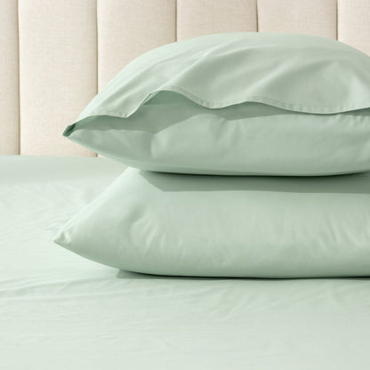 Two pillows stacked on a bed with percale pillowcases on them
