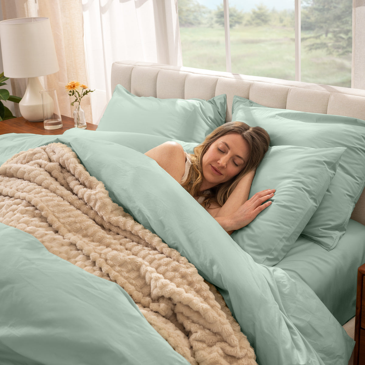 Woman sleeping in a bed with percale bedding and beige blanket
