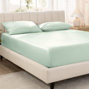 Bed with fitted sheet and pillowcases in a bright room.