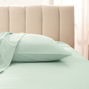 Sateen pillowcase on a bed with a beige headboard