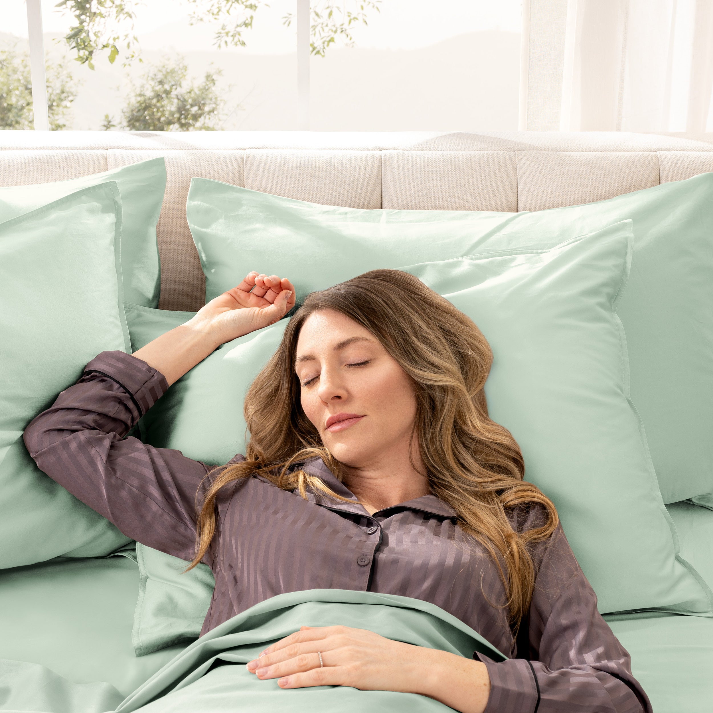 Woman sleeping peacefully in a bed made with sateen sheets and pillowcases.