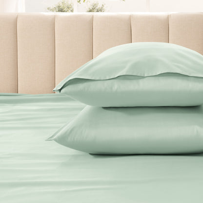 Two pillows stacked on a bed with a beige headboard.