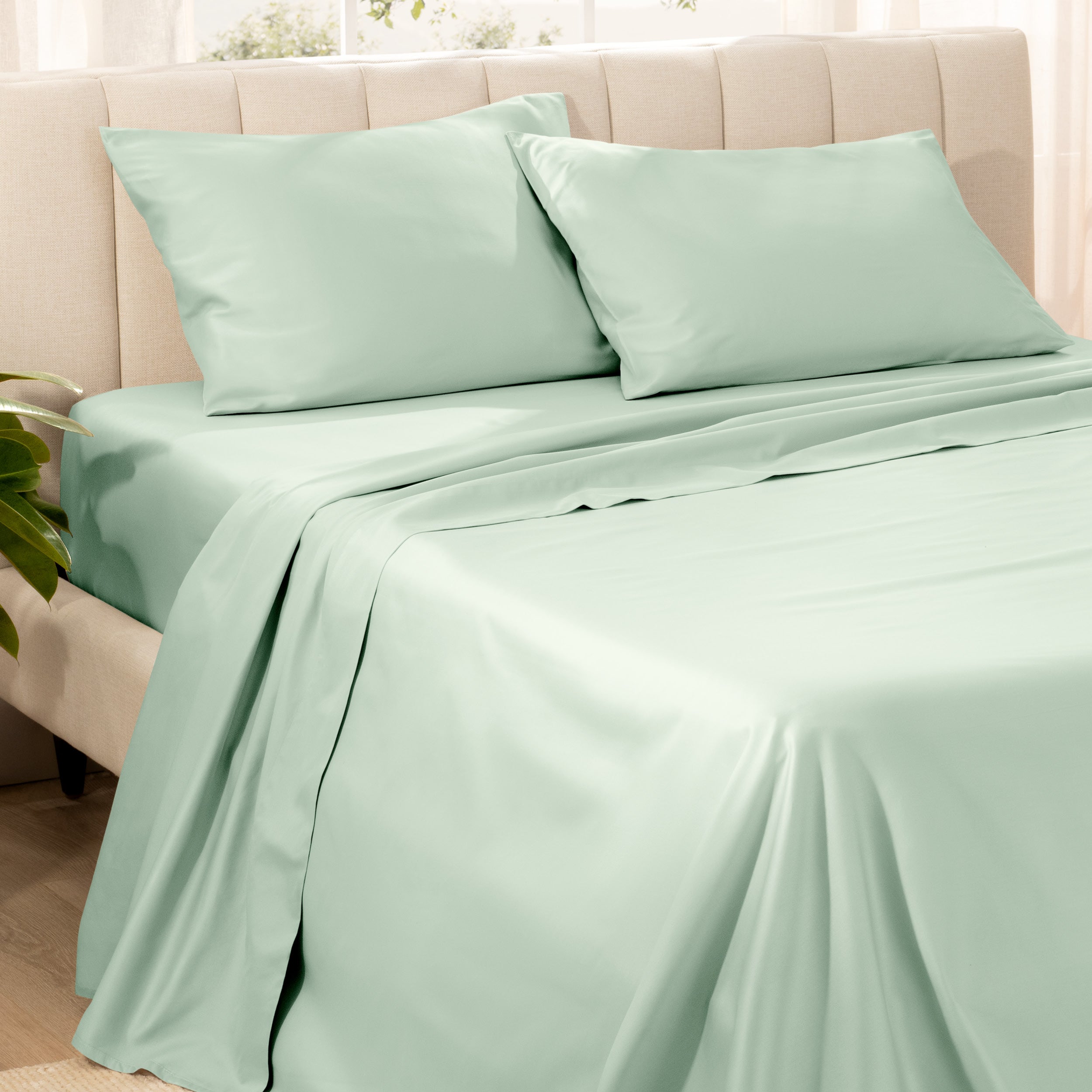 Bedding set on a bed with pillows in a bright room.