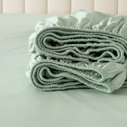 Folded fitted sheet on a bed with a neutral background