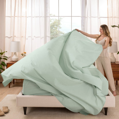 Woman putting a sheet set on a bed in a bright bedroom.