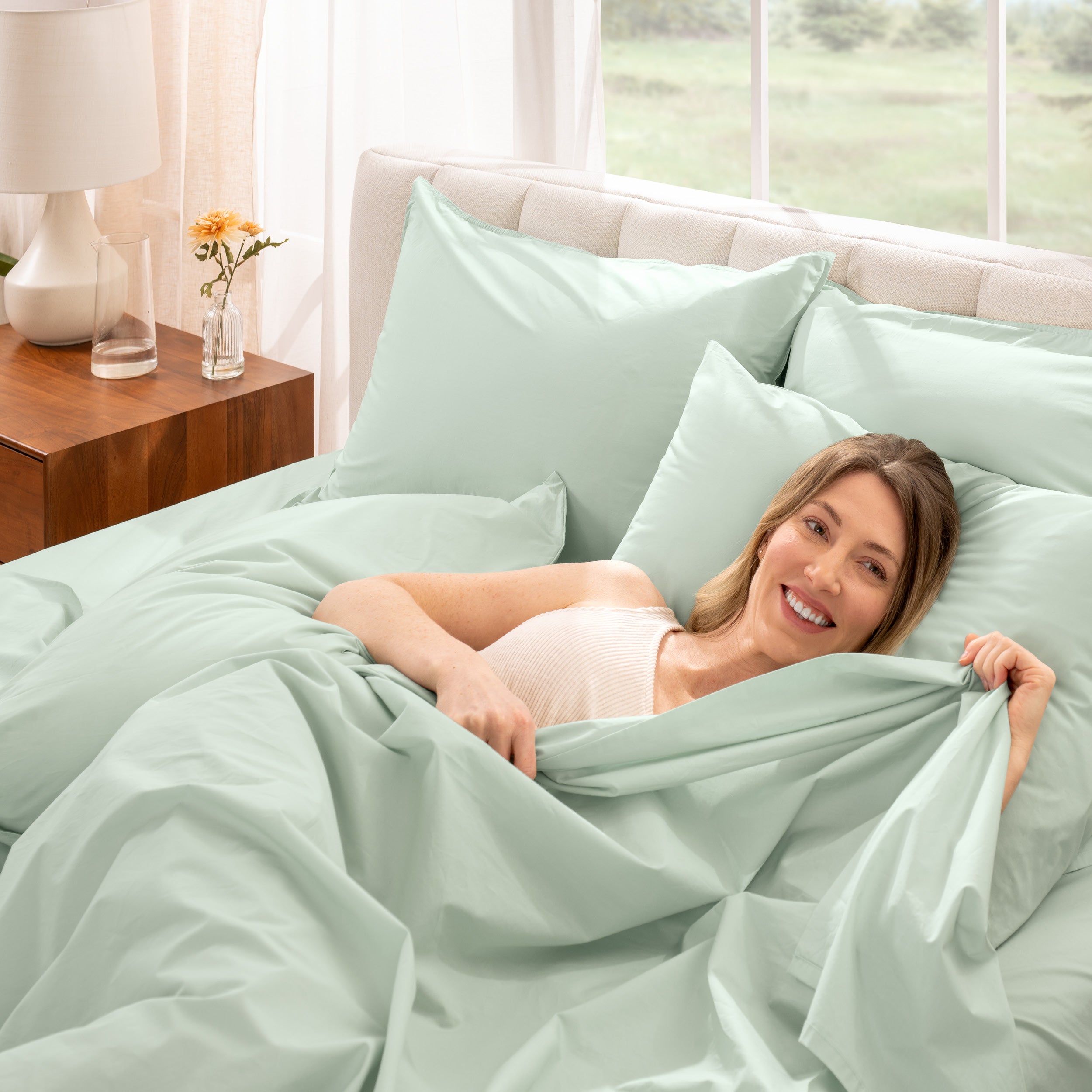 A woman is lying on a bed make with percale sheets and pillowcases