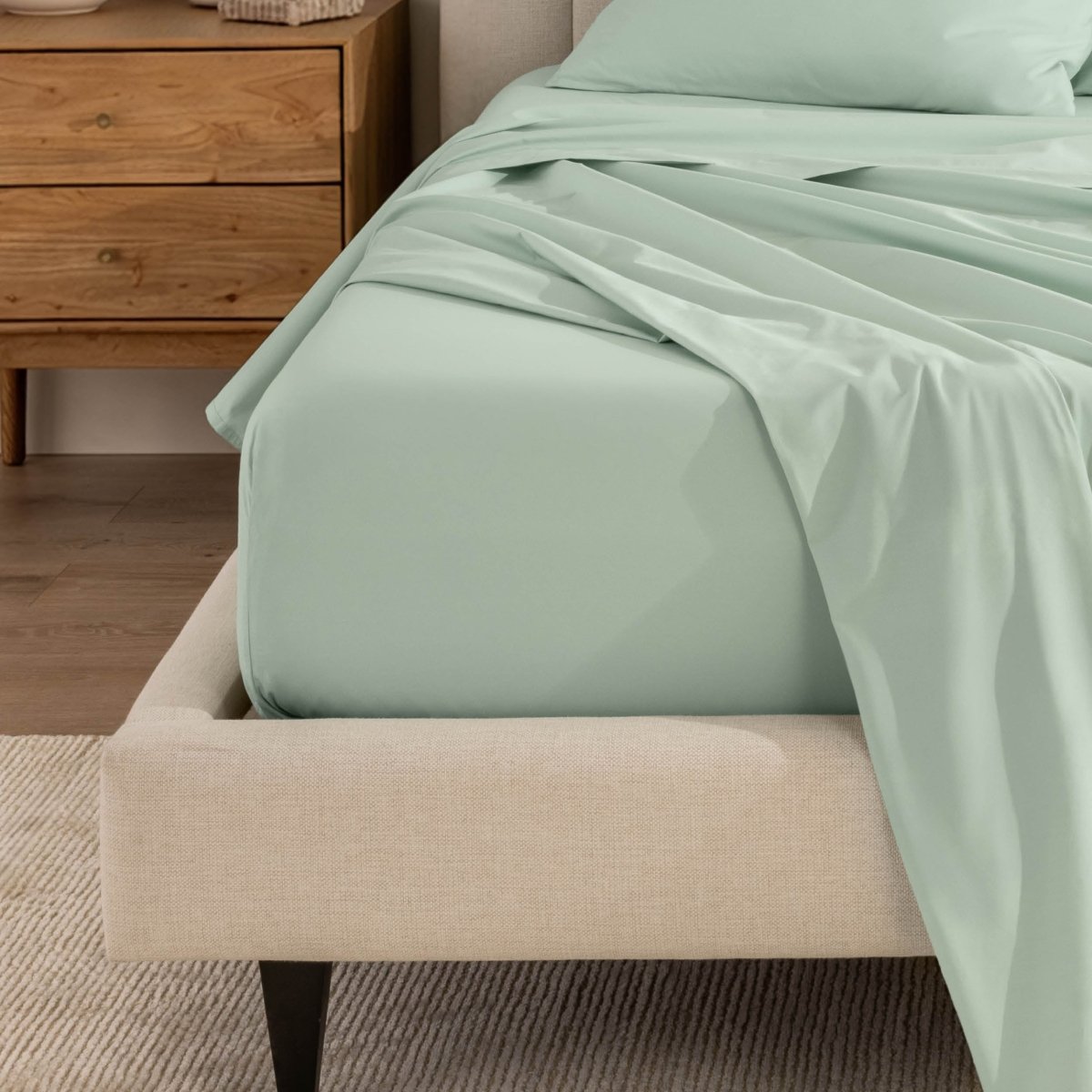 Top sheet and a matching fitted sheet on a bed with a beige bed frame