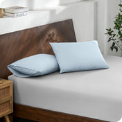 Diagonal view of modern wood bed with a fitted sheet and pillowcases