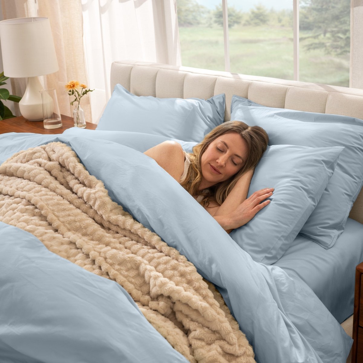 Woman sleeping on a bed made with percale sheets and duvet cover