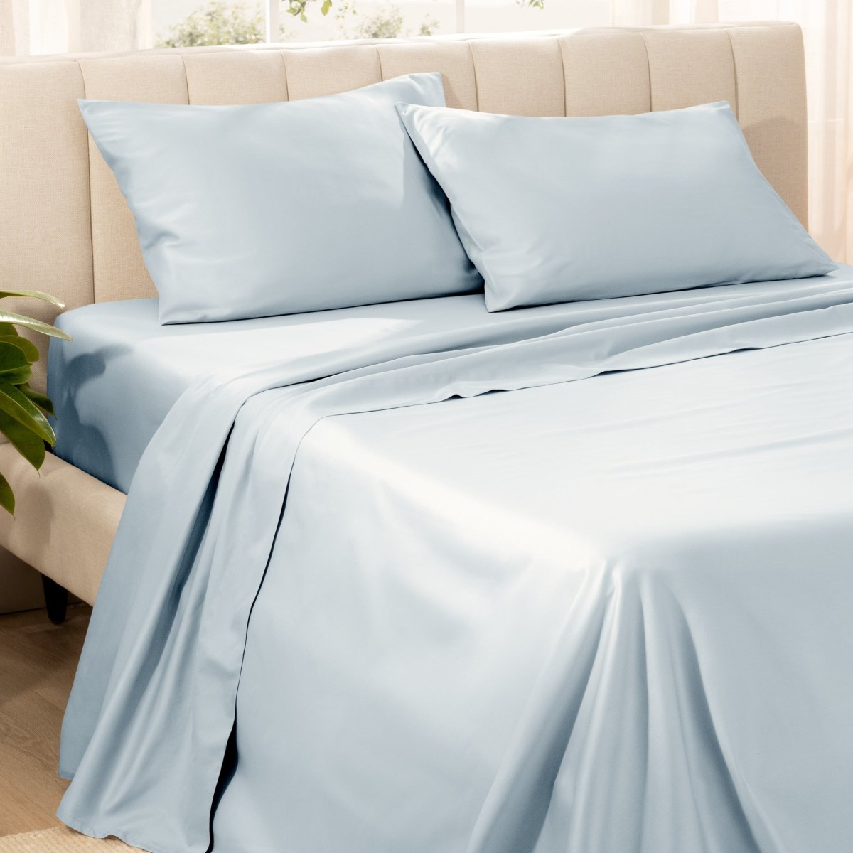 Bedding set on a bed with pillows in a bright room.