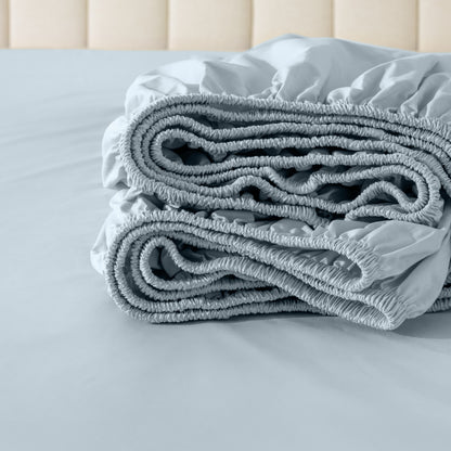 Folded fitted sheet on a bed with a neutral background
