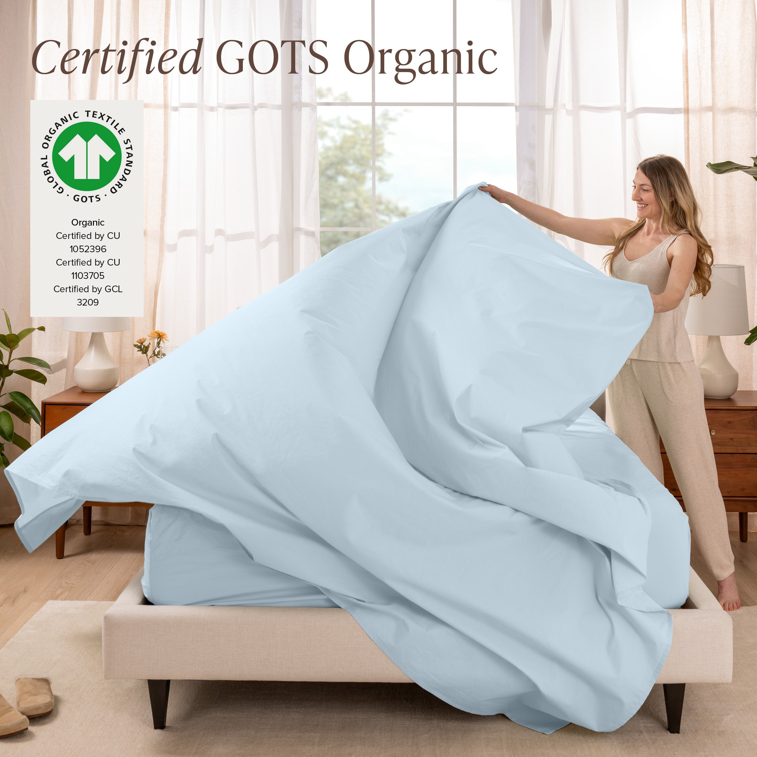 A woman is making a bed with organic cotton percale sheets