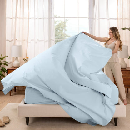 Woman putting a sheet set on a bed in a bright bedroom.
