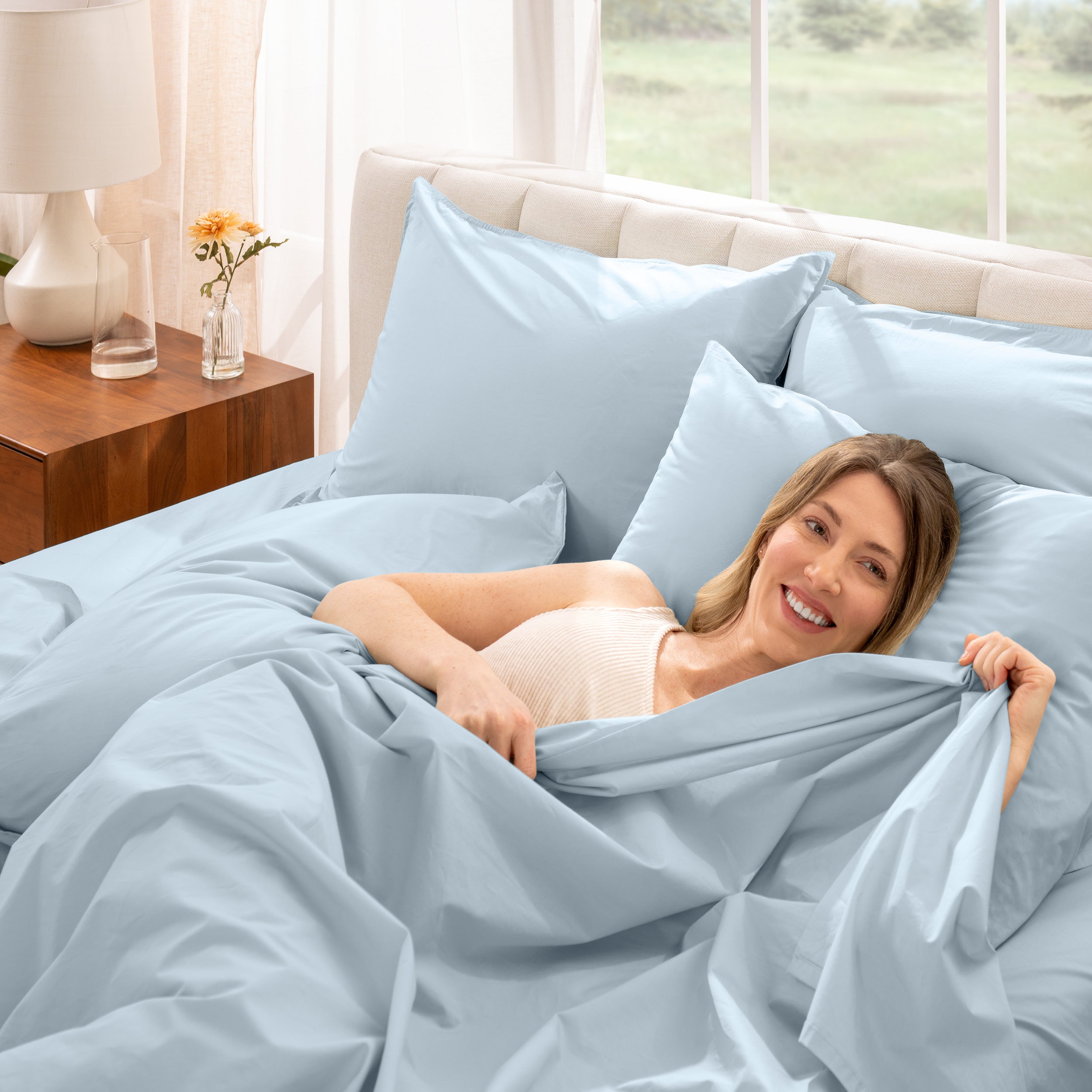 A woman is lying on a bed make with percale sheets and pillowcases